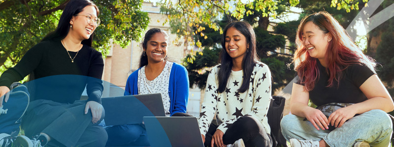 students sitting in garden with laptop